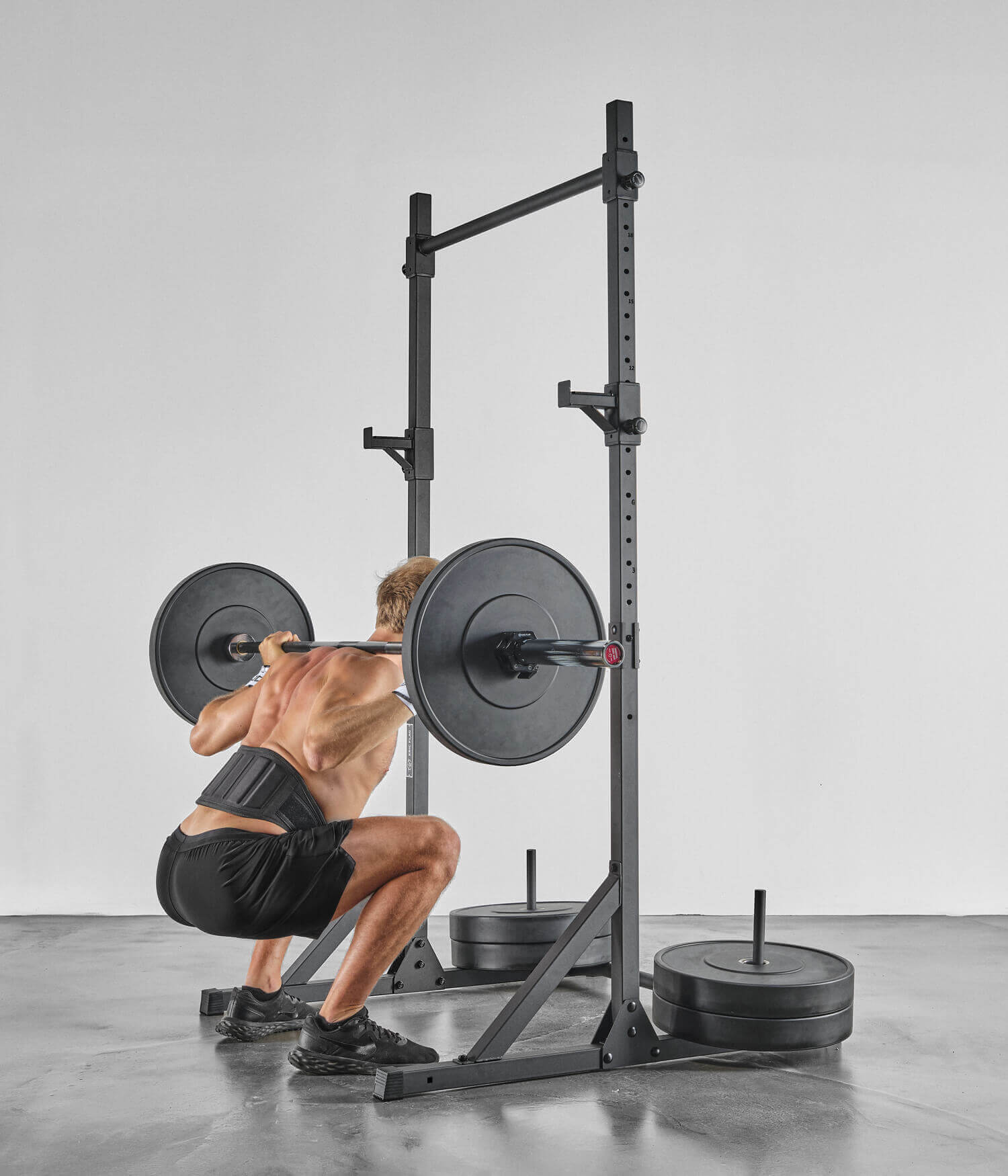 Man training with Stabilizing Columns - Pull-up Bar and weights, in full squat.