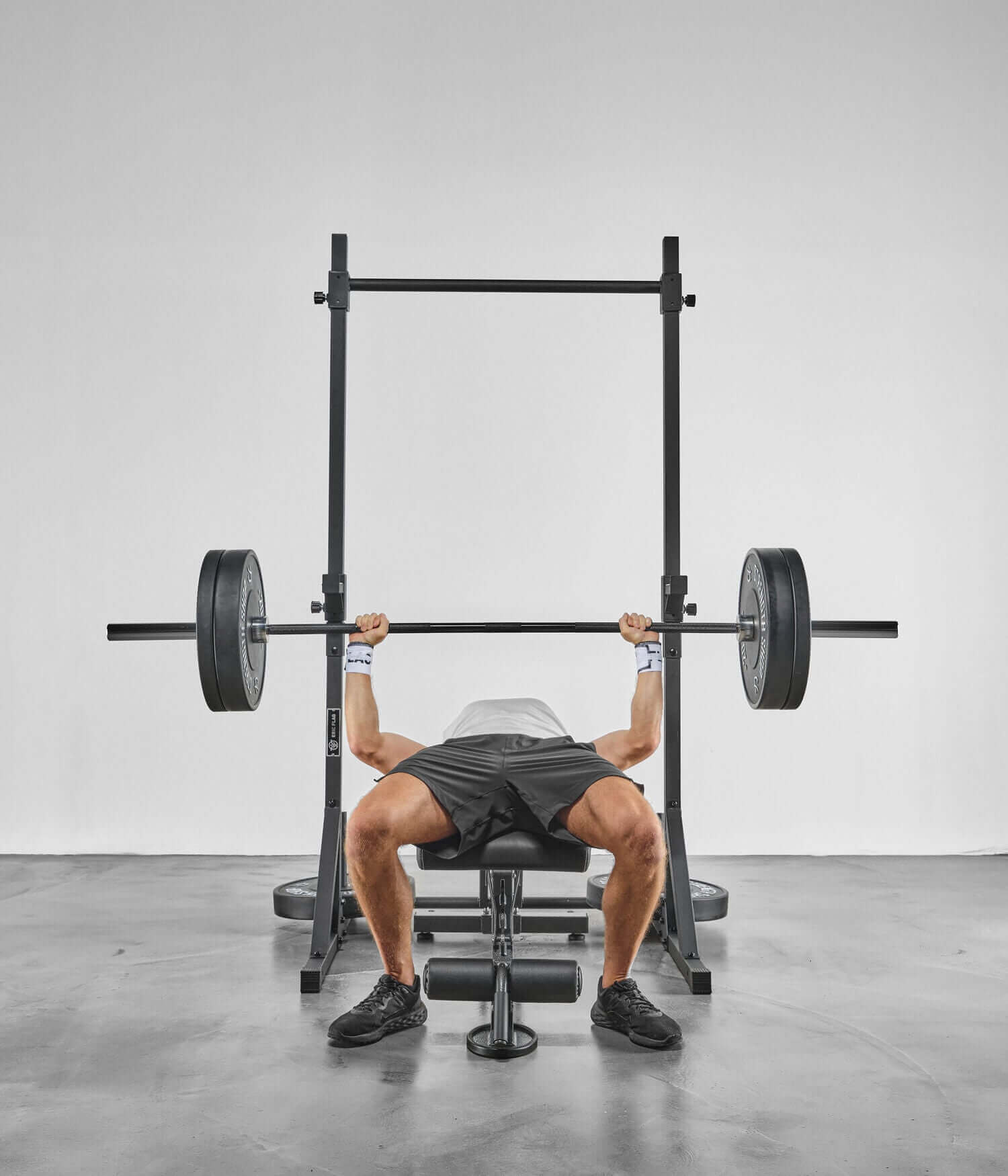 Person lifting weights using Colonnes de Stabilisation - Barre de Traction in a gym setting.